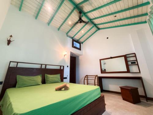 - une chambre avec un lit vert et un miroir dans l'établissement Black Lantern, à Matara