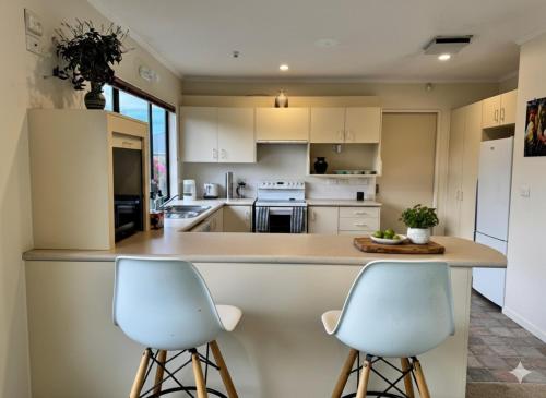 a kitchen with two white stools at a counter at Wellington Suburb Stay in Wellington