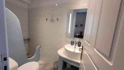 a white bathroom with a sink and a toilet at Akrogiali studios in Donoussa