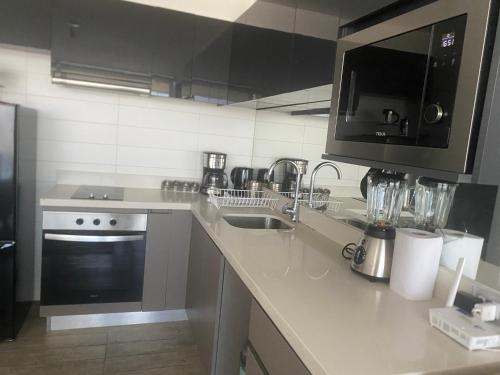 a kitchen with a counter with a sink and a microwave at Concón Apartment in Concón