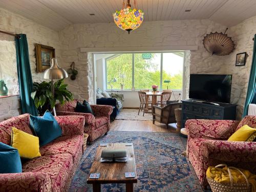 a living room with couches and a table at Lofthouse - secluded quirky cottage with sea views! in Newport