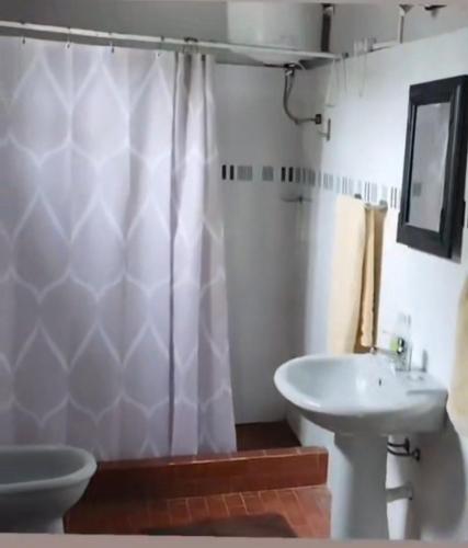 a bathroom with a white shower curtain and a sink at Ruma in Bella Unión