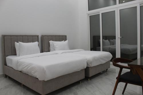 een slaapkamer met een groot bed met witte lakens en kussens bij Masfout Mountains View in Sinādil