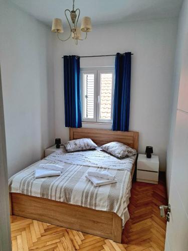 a bedroom with a bed with blue curtains and a window at Old town nest in Budva