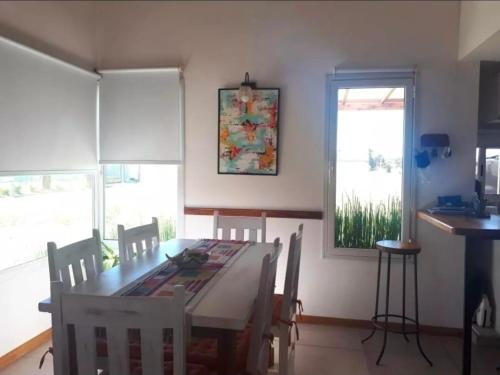 una sala da pranzo con tavolo, sedie e una finestra di Cabaña Marilau a Santa Clara del Mar