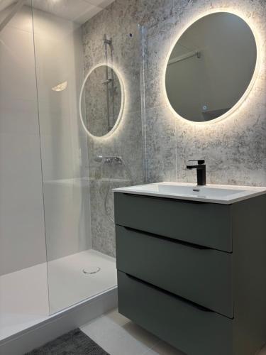 une salle de bain avec un lavabo et une douche avec un miroir dans l'établissement Maison bord de mer normandie, à Langrune-sur-Mer