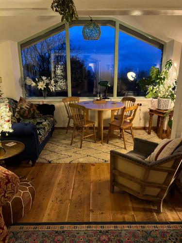 a living room with a table and chairs and a large window at Lofthouse - secluded quirky cottage with sea views! in Newport