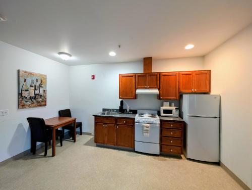 een keuken met houten kasten, een tafel en een koelkast bij Ponderosa Motel in Goldendale