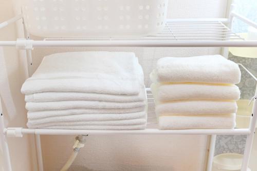 a stack of towels on a shelf in a bathroom at 民泊 Ichinomiya K Room 1A in Ichinomiya