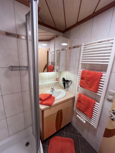 a bathroom with a sink and a shower with orange towels at Badmeisterhof in Leogang