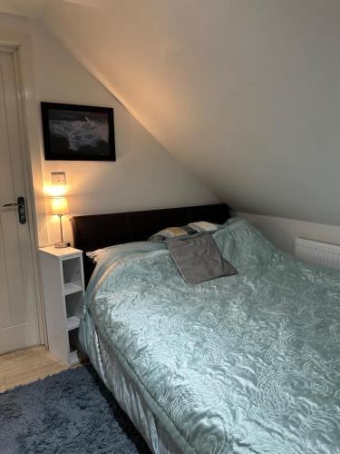 a bedroom with a bed with a green comforter at A Cosy and Luxurious Studioflat in Navestock