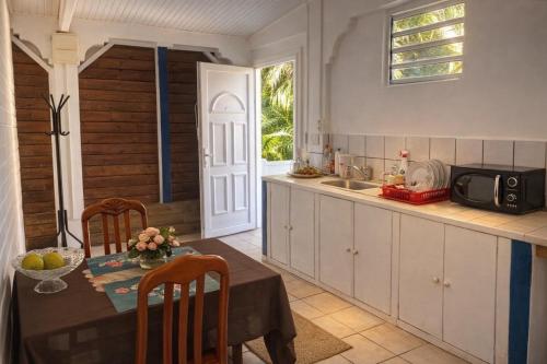 a kitchen with a table and a microwave at Cocon Douillet à 10 min du Marin in Le Marin