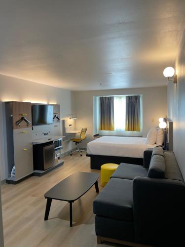 巴吞鲁日巴敦罗吉机场麦克罗特套房酒店的一间酒店房间，里面有一张床和一张沙发