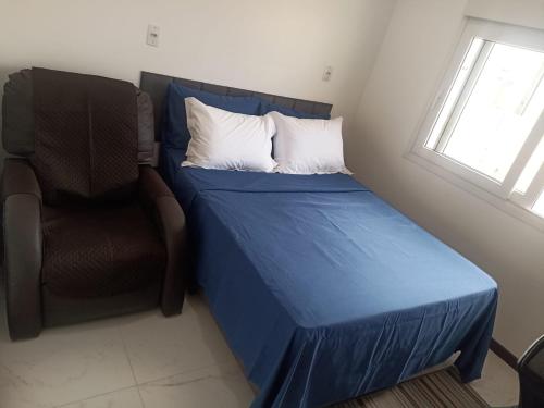 a bed and a chair in a room at Studio Campeche in Florianópolis