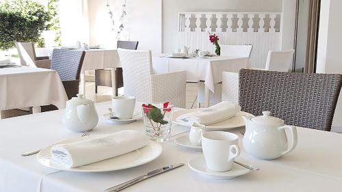 een witte tafel met witte borden en keukengerei erop bij Akrogiali Exclusive Hotel (Adults Only) in Polykhrono