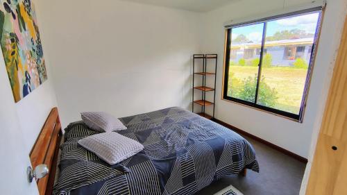ein kleines Schlafzimmer mit einem Bett mit Fenster in der Unterkunft Cabañas en la naturaleza in Villarrica