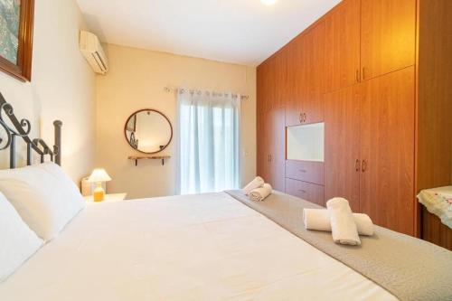 een slaapkamer met een groot wit bed en houten kasten bij Kalemi House in Kato Korakiana