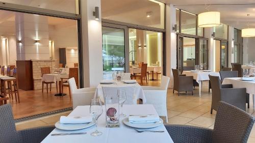 a dining room with white tables and chairs at Akrogiali Exclusive Hotel (Adults Only) in Polychrono