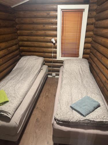 two beds in a room with wooden walls at Øse Camping in Gratangen