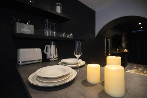 a table with two candles and plates and wine glasses at Les clés du désir in Épône