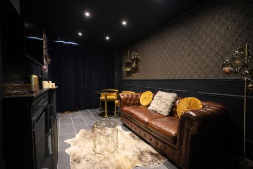 a living room with a brown leather couch and a table at Les clés du désir in Épône