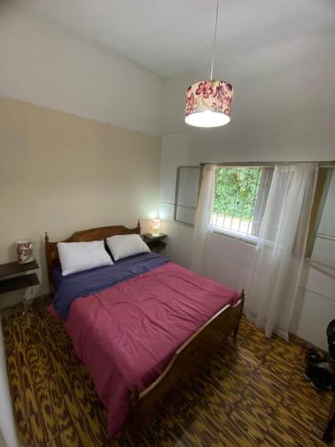 een slaapkamer met een bed, een raam en een kroonluchter bij Villa Messina, Casa di Vacanza in Juana Koslay 