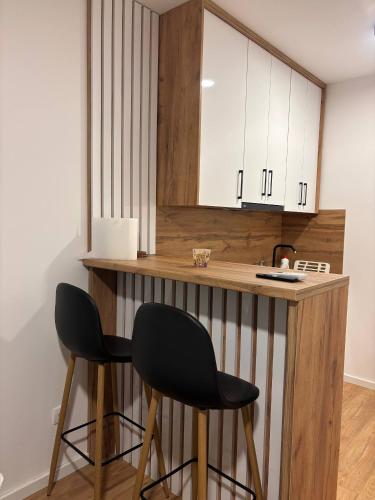 a kitchen with two black chairs at a counter at Apartman S52 City Centre in Doboj