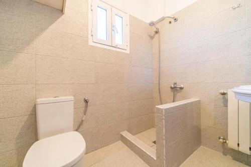 een badkamer met toilet, wastafel en raam bij Kalemi House in Kato Korakiana