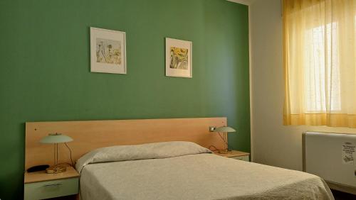 a bedroom with green walls and a bed with two lamps at Hotel Ariston Imperial in Porto Garibaldi
