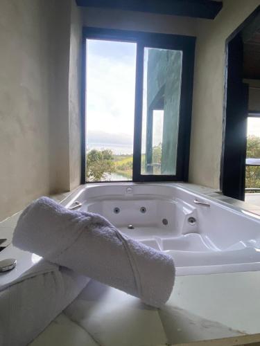 een badkamer met een wit bad en een raam bij Chalé da lagoa in Paraibuna