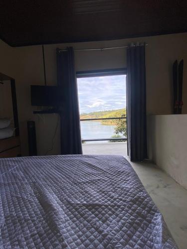 een slaapkamer met een bed en een groot raam bij Chalé da lagoa in Paraibuna