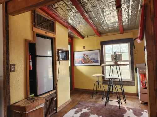 Cette chambre comprend un réfrigérateur, une table et des chaises. dans l'établissement Bigfoots Bungalow, à Bandera
