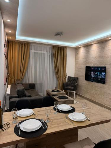 ein Wohnzimmer mit einem Tisch mit Tellern und Weingläsern in der Unterkunft Hil Obrenovac in Obrenovac