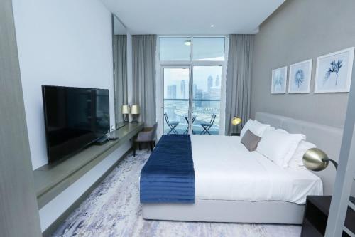 ein Hotelzimmer mit Bett und Flachbildfernseher in der Unterkunft Damac Maison Prive Deluxe Studio with Water Canal View in Dubai