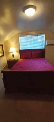 een slaapkamer met een bed met een paarse sprei en een raam bij Historic Reno Home in Reno