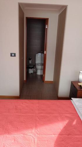 een slaapkamer met een toilet en een rode sprei bij Departamentos en Edificio Distrito Cavancha 1 in El Cerrillo