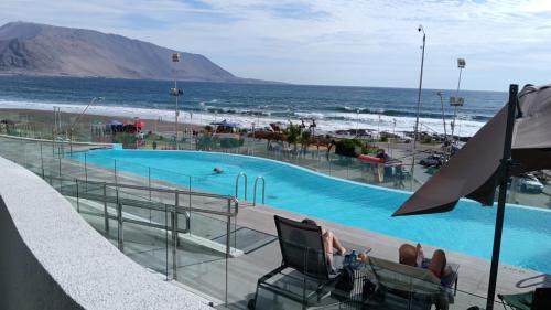een zwembad met de oceaan op de achtergrond bij Departamentos en Edificio Distrito Cavancha 1 in El Cerrillo