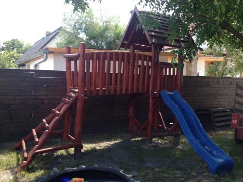 a wooden playground with a slide and a slideintendangering at Famvarga Apartmanház in Balatonfenyves