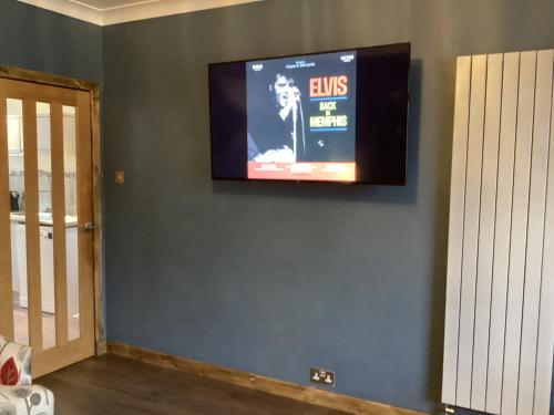 een televisie aan een muur in een kamer bij Charlies in Huntly