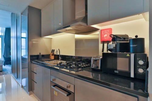 a kitchen with a stove top and a microwave at Damac Maison Prive Deluxe Studio with Water Canal View in Dubai