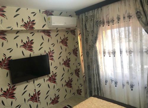een kamer met een televisie aan een muur met bloemenbehang bij Apartament central in Ploieşti