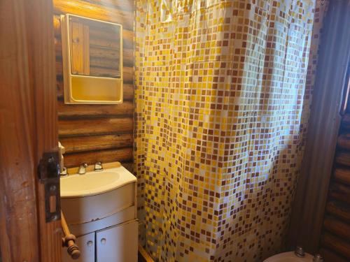 a bathroom with a sink and a yellow tiled shower curtain at Cabañas Lumel in Carpintería