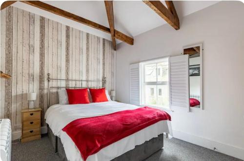 a bedroom with a bed with red pillows and a window at Corner Cottage Mevagissey in Mevagissey
