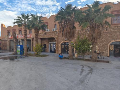 een gebouw met palmbomen ervoor bij Hotel El Golla in Er Rachidia