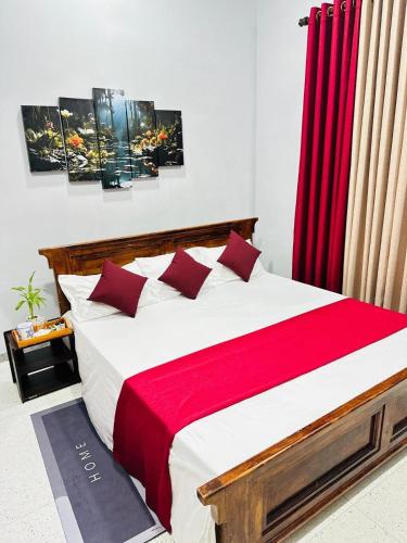 a bedroom with a large bed with red curtains at MSGuest House in Jaffna