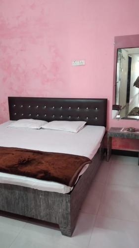 a bed in a room with a pink wall at Shikhar guest house 1 in Ujjain