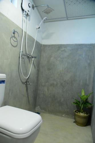 La salle de bains est pourvue d'une douche, de toilettes et d'une plante. dans l'établissement Arcadia Resort, à Hikkaduwa