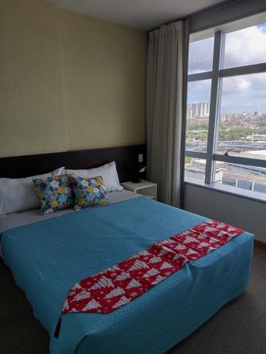 a bedroom with a large bed with a large window at Bussines Flat Iguatemi in Salvador