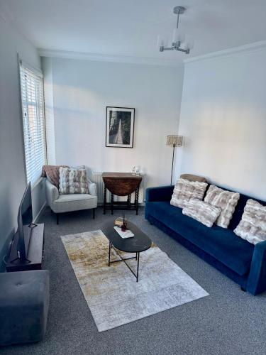 a living room with a blue couch and a table at Luxury Three Bedroom Duplex Apartment Torquay Marina in Torquay