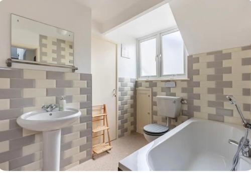 a bathroom with a sink and a tub and a toilet at Corner Cottage Mevagissey in Mevagissey